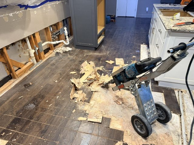 Damaged hardwood flooring removal showing subfloor underneath after water damage