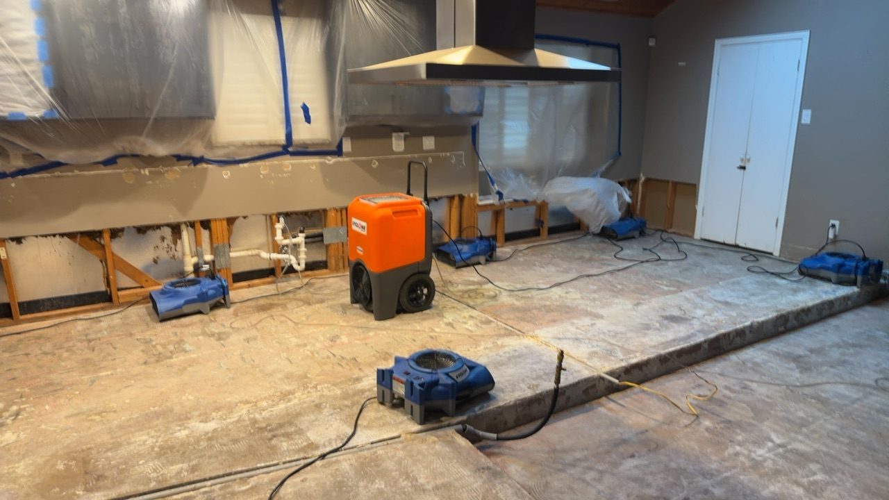 Large orange dehumidifier and air movers in a kitchen during a major water damage restoration job
