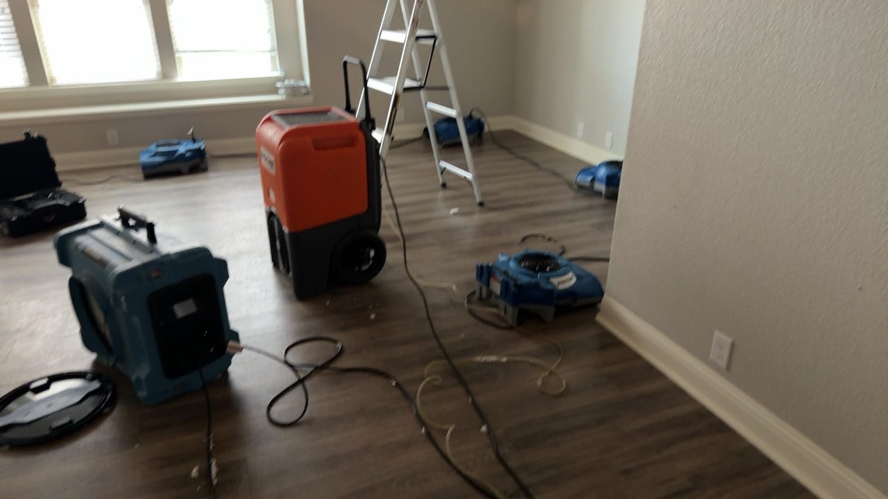 Living room water damage equipment including dehumidifier, air movers, and ladder set up for structural drying