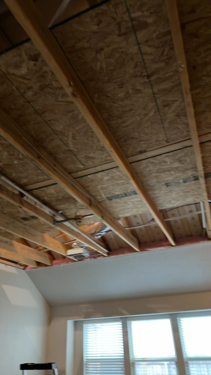 Wall cavities exposed during water damage repair with copper pipes visible and structural drying setup